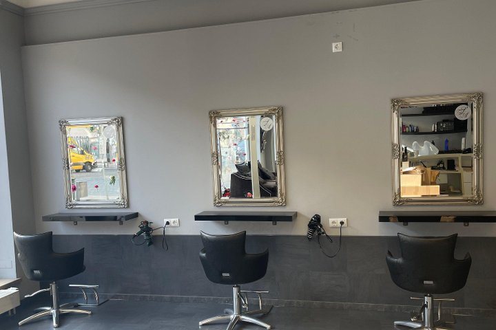 Drei Friseur-Bedienplätze im Lifestyle-Ink Studio mit silbergerahmten Spiegeln und schwarzen Ledersesseln.